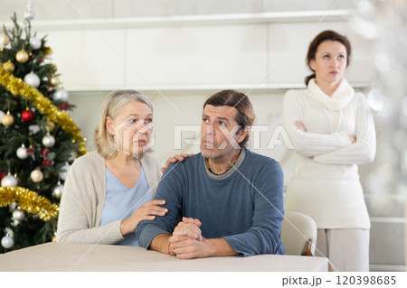 Senior woman sits near adult son and comforts him in quarrel with wife during winter holiday 120398685