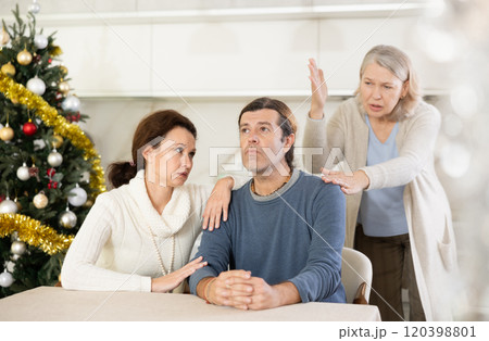 Woman sits near man and comforts during quarrel with senior mom on Christmas Eve Woman sits near man and comforts during quarrel with senior mom on Christmas Eve 120398801