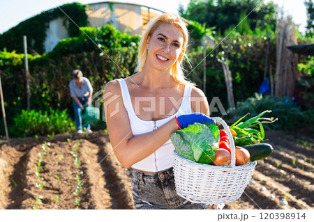 Cheerful girl with fresh vegetable harvest in backyard garden 120398914