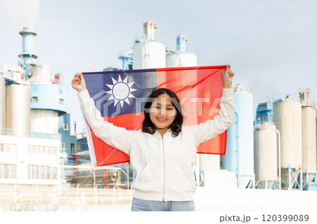 Happy asian girl with flag of taiwan standing in front of industrial scenery 120399089