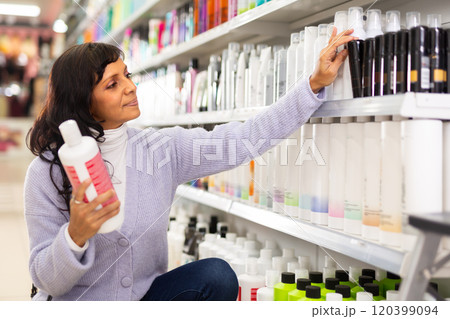 Latin american woman looking for haircare products at cosmetics shop 120399094