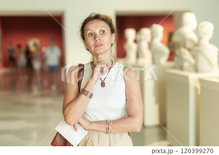 Woman looks at museum sculptures with brochure Woman looks at museum sculptures with brochure 120399270