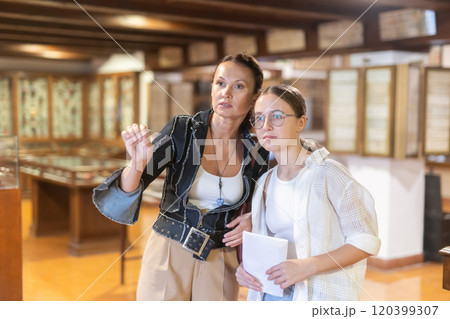 Woman and teenage girl looking at exhibit in museum 120399307