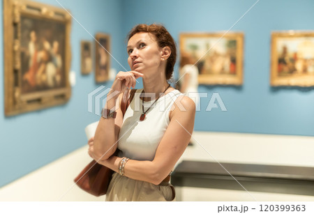 Closeup on attentive woman visiting museum and looking at exhibition of paintings Closeup on attentive woman visiting museum and looking at exhibition of paintings 120399363