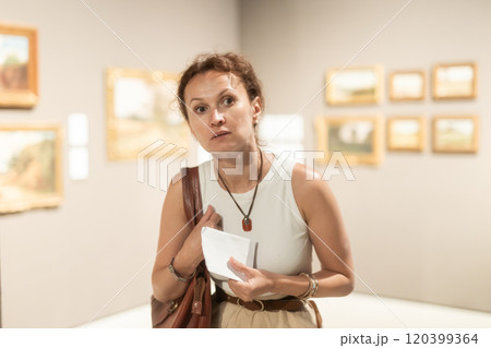 Woman viewing art gallery with brochure Woman viewing art gallery with brochure 120399364