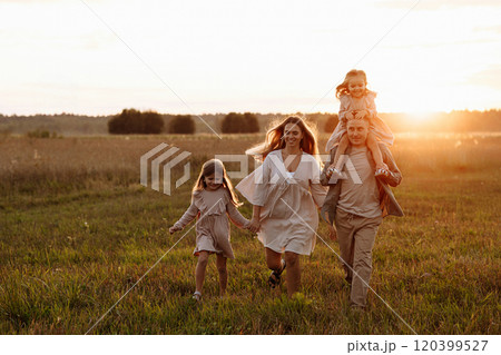 A family of four is walking through a field of tall grass 120399527