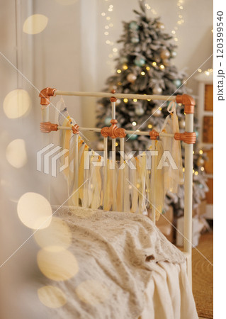 Kids bedroom with a retro bed with a and lace pillows and a decorated Christmas tree. 120399540