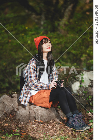 カメラを持ちながら登山する女性 120399669