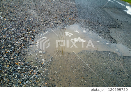 駐車場のアスファルトが劣化して水たまりができる 120399720