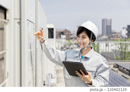 室外機を点検する女性作業員 120402120