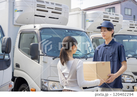 担当地域の配達員に荷物を渡す事務員 120402294