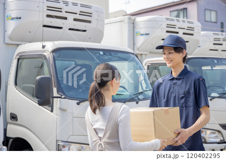 担当地域の配達員に荷物を渡す事務員 120402295