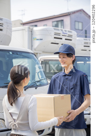 担当地域の配達員に荷物を渡す事務員 120402296
