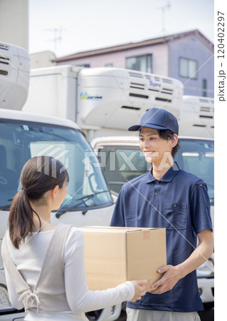 担当地域の配達員に荷物を渡す事務員 120402297