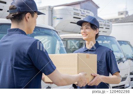 担当地域の配達員に荷物を渡す同僚 120402298