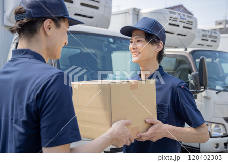 担当地域の配達員に荷物を渡す同僚 120402303