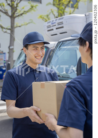 担当地域の配達員に荷物を渡す同僚 120402306