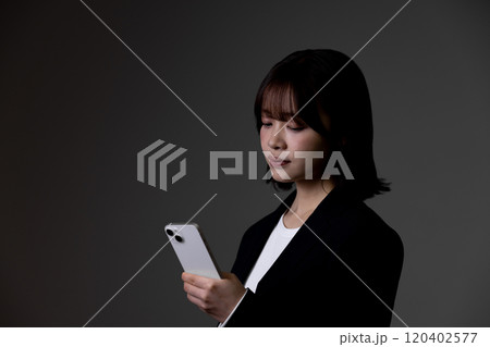 スマートフォンを使うビジネスウーマン 黒背景 黒バック スマートフォンを使うビジネスウーマン 黒背景 黒バック 120402577