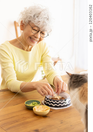 猫の餌を準備するシニア女性 猫の餌を準備するシニア女性 120403162
