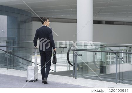 ビジネスバッグとキャリーケースを持って歩く40代のビジネスマン 120403935