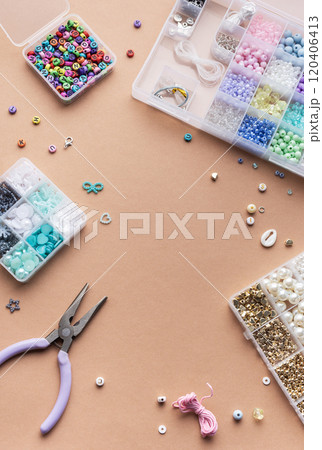 Crafting with colorful beads on a flat workspace with tools and containers in bright daylight Crafting with colorful beads on a flat workspace with tools and containers in bright daylight 120406413