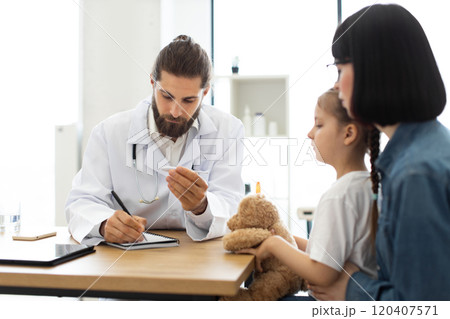 Doctor examining young girl with mother in medical office 120407571