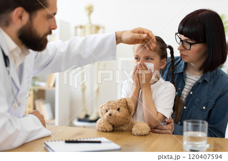 Caring doctor examines child with a runny nose at clinic 120407594