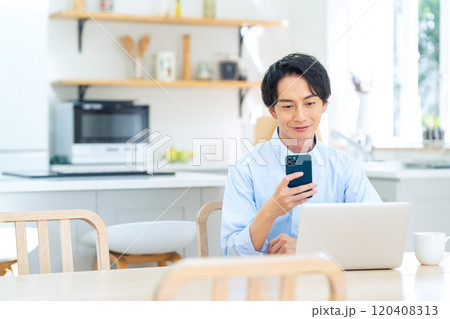 リビングでテレワークをする若い男性 120408313