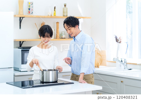 キッチンで料理をする若い夫婦 120408321