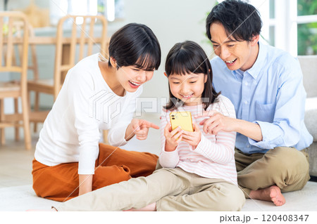 スマホを見ながらリビングでくつろぐ家族 120408347