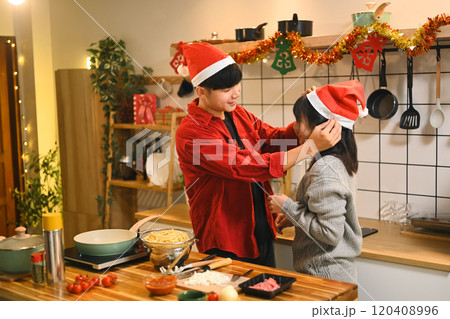 Beautiful young couple in Santa hats cooking together at Christmas winter holidays 120408996