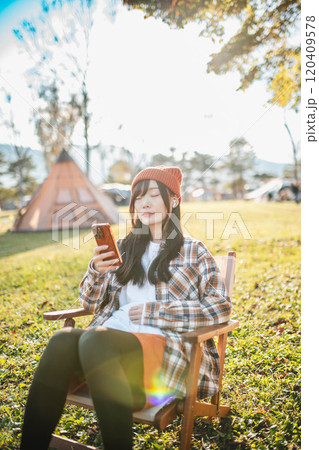 キャンプ場で座りながら音楽を聴く女性 キャンプ場で座りながら音楽を聴く女性 120409578
