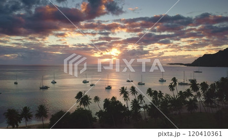 Sailboats yachts anchor in tropical island sea bay lagoon. Palm trees beach, vibrant clouds sunset sky. Remote wild nature paradise, exotic summer luxury travel tour. Natural background. Drone shot Sailboats yachts anchor in tropical island sea bay lagoon. Palm trees beach, vibrant clouds sunset sky. Remote wild nature paradise, exotic summer luxury travel tour. Natural background. Drone shot 120410361