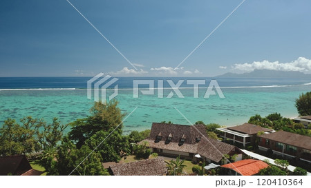 Resort bungalows on Tahiti island coastline, turquoise ocean lagoon, coral reefs, green lush vegetation, Moorea in background. Drone fly over hotel roofs. Remote nature paradise, exotic summer travel 120410364