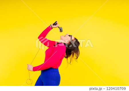 Smiling brunette woman with microphone on colored studio background 120410709