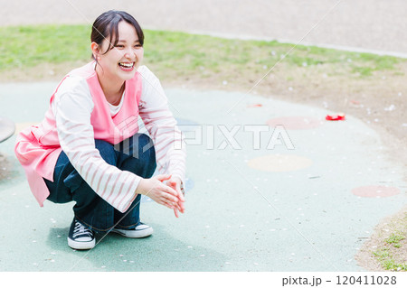 遊具の前で子供と遊ぶ保育士 120411028