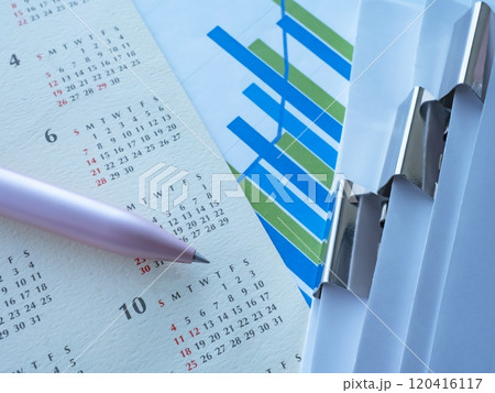 テーブルに置かれたグラフとカレンダーと書類 120416117