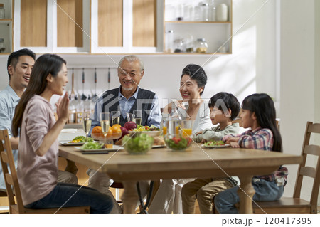 asian family chatting while eating meal asian family chatting while eating meal 120417395