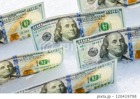 us dollar banknotes standing on their side on the snow surface at sunny winter day 120419798