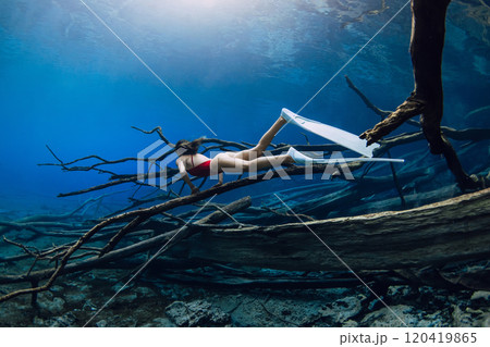 Free diver beauty woman glides and posing with fins over sunken logs in the lake. Free diving in blue crystal lake 120419865