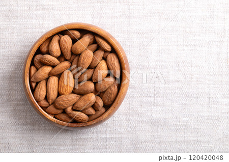 Almonds in a wooden bowl on linen fabric, with empty space for text. Shelled, raw, whole and dried nuts, seeds and fruits of Prunus dulcis. Ready-to-eat as snack, or used as an ingredient for baking. Almonds in a wooden bowl on linen fabric, with empty space for text. Shelled, raw, whole and dried nuts, seeds and fruits of Prunus dulcis. Ready-to-eat as snack, or used as an ingredient for baking. 120420048
