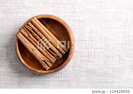Ceylon cinnamon sticks in a wooden bowl on linen, with empty space for text. Parallel arranged whole, dried bark strips of Cinnamomum verum, used mainly as aromatic condiment and flavouring additive. Ceylon cinnamon sticks in a wooden bowl on linen, with empty space for text. Parallel arranged whole, dried bark strips of Cinnamomum verum, used mainly as aromatic condiment and flavouring additive. 120420050