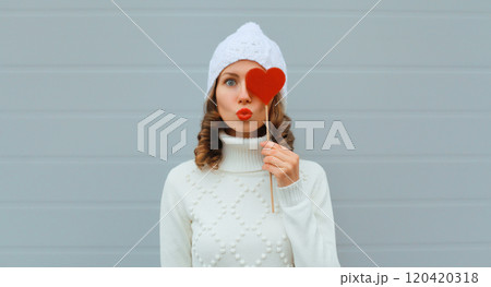 Winter christmas portrait of beautiful happy young woman blowing kiss with lollipop in white hat Winter christmas portrait of beautiful happy young woman blowing kiss with lollipop in white hat 120420318