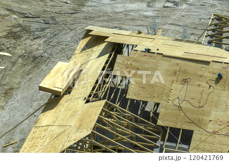 Professional builders working on roof construction of unfinished suburban home with wooden frame structure in Florida rural area. Concept of housing development in America 120421769