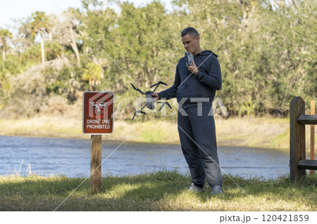 Operator is disappointed because he can not fly his quadcopter in national park no drone area. Man is unable to use his UAV near restriction notice sign Operator is disappointed because he can not fly his quadcopter in national park no drone area. Man is unable to use his UAV near restriction notice sign 120421859