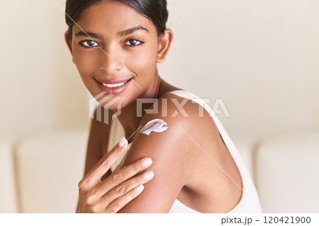 Woman Smiling While Applying Skincare Cream on Shoulder at Home Woman Smiling While Applying Skincare Cream on Shoulder at Home 120421900