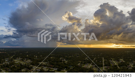 Landscape of dark ominous clouds forming on stormy sky during heavy thunderstorm over rural town area at sunset Landscape of dark ominous clouds forming on stormy sky during heavy thunderstorm over rural town area at sunset 120421943