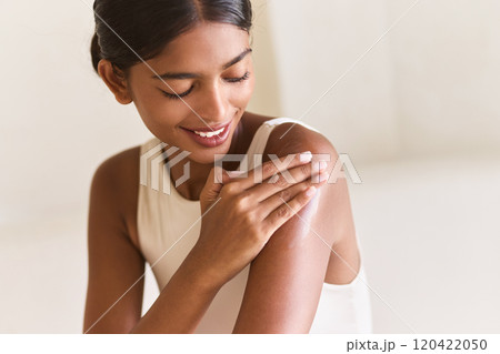 Woman Smiling While Applying Moisturizer for Healthy Glowing Skin Care Routine Woman Smiling While Applying Moisturizer for Healthy Glowing Skin Care Routine 120422050