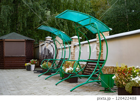 Outdoor swing bench with canopy on a tiled patio. Outdoor swing bench with canopy on a tiled patio. 120422488