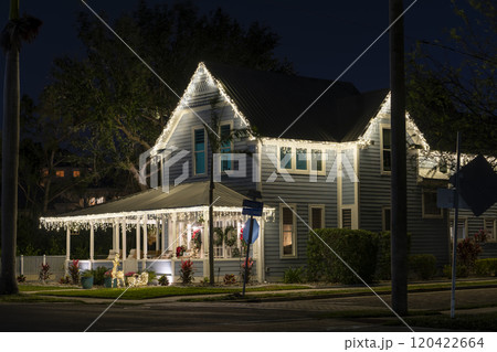 House front yard with big porch brightly illuminated with Christmas decorations. Outside decor of Florida family home for winter holidays 120422664